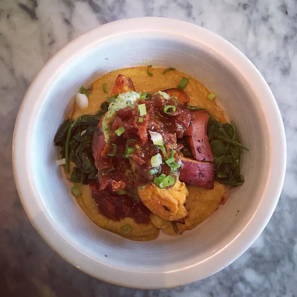 A bowl of creamy red lentil dal with golden tadka-infused oil and fresh cilantro on top, served with rice