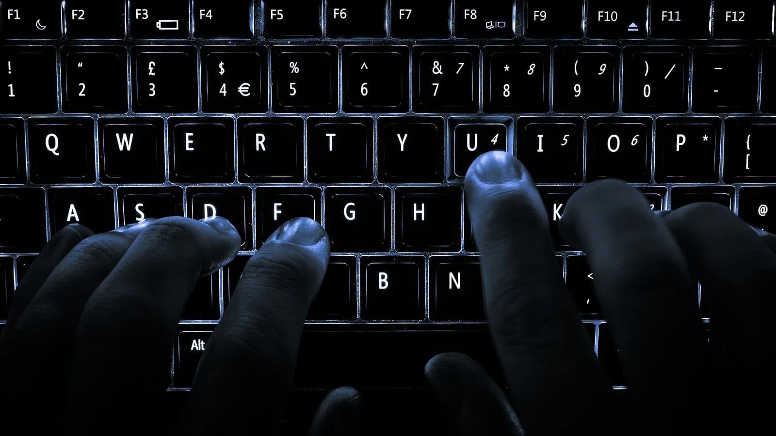 Two hands typing on a backlit laptop keyboard in a dark room, photographed on 26 December 2013, a stock photograph illustrative of computer use and not of any OpenAI product