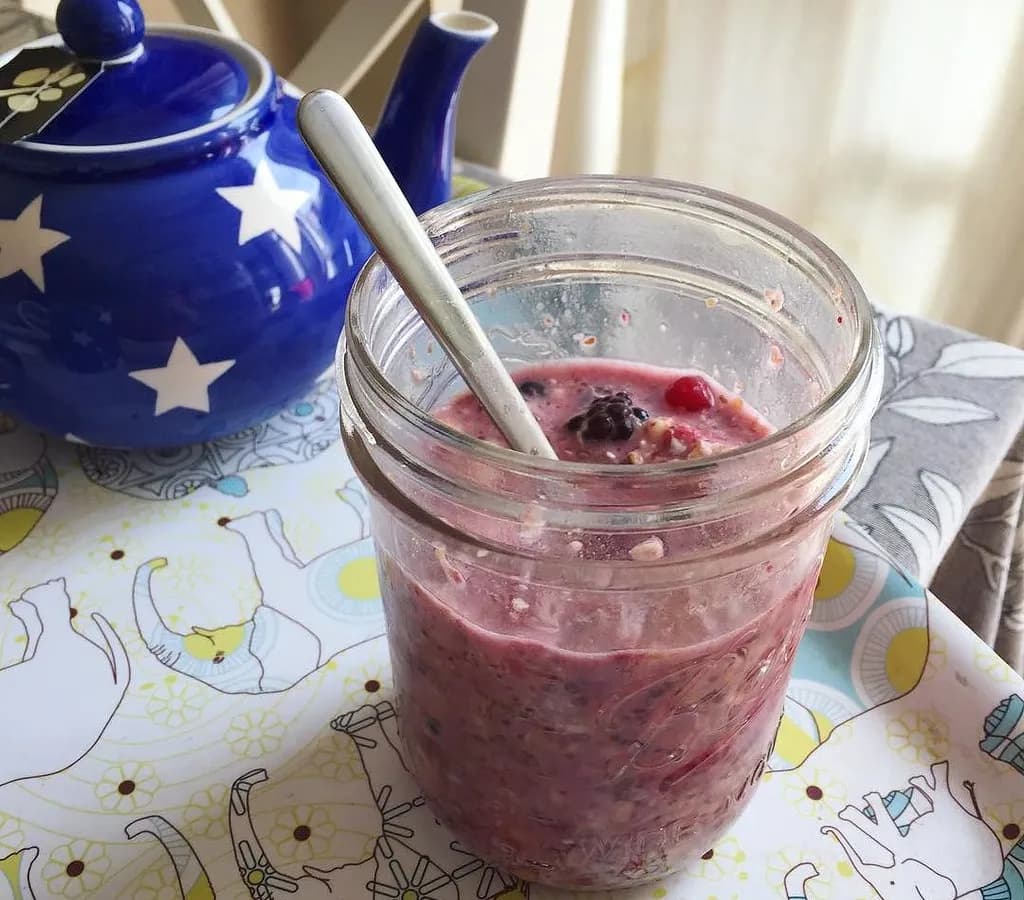Three clear jars of overnight oats with different toppings: berries with almonds, tropical fruit with coconut, and apples with granola
