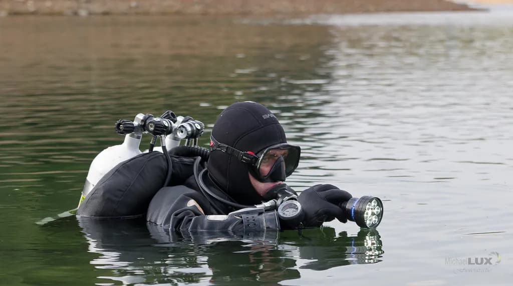 A technical diver equipped with multiple sidemounted gas cylinders preparing to descend