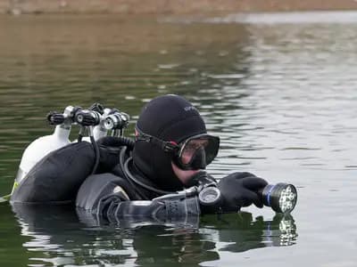 A technical diver equipped with multiple sidemounted gas cylinders preparing to descend