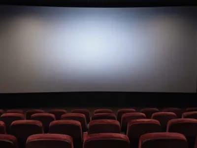 An empty cinema auditorium with rows of seats facing a blank screen