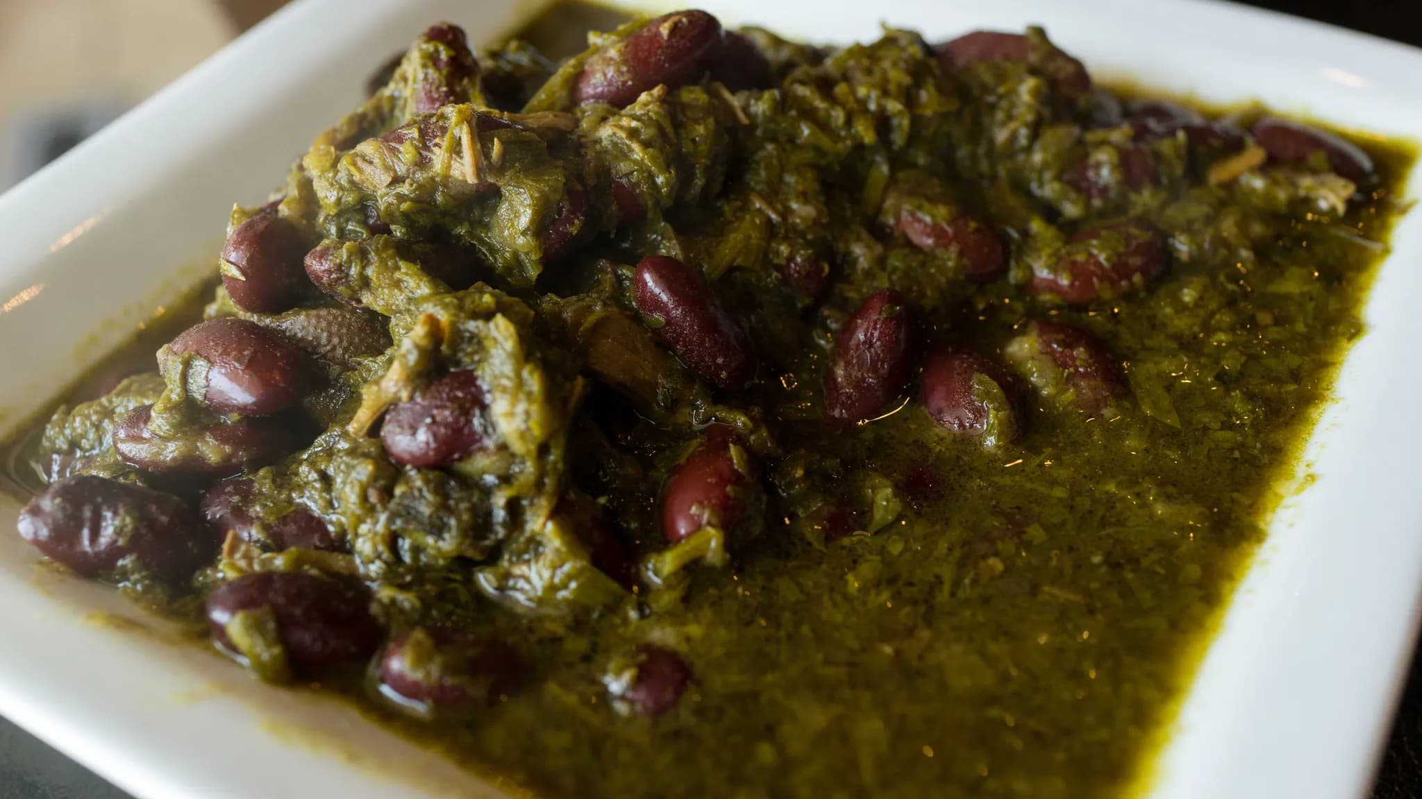 Bowl of fragrant Persian ghormeh sabzi stew with tender meat, kidney beans, and fresh herbs served over golden saffron rice