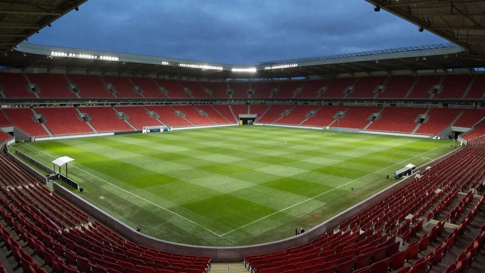 A floodlit football stadium in the evening before kick-off