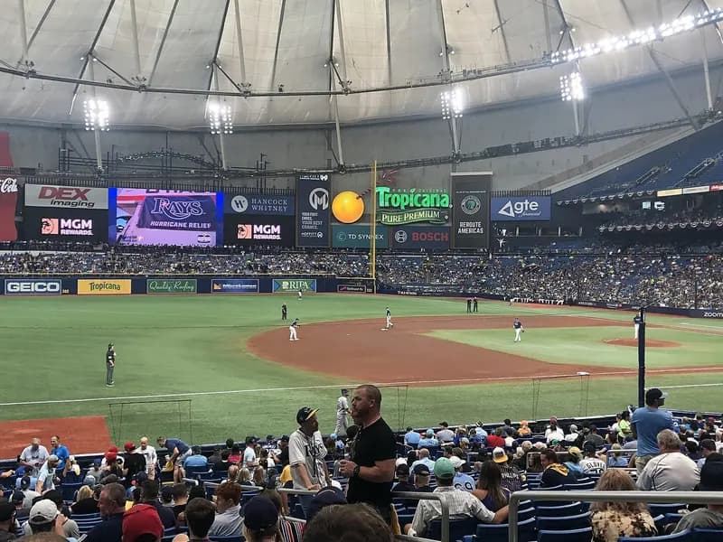 The domed interior of Tropicana Field in St. Petersburg, Florida, with its green field, red infield dirt, outfield signs and a crowd in the stands, photographed on 4 October 2023, a file photograph of the ballpark and not of Tuesday's World Series game