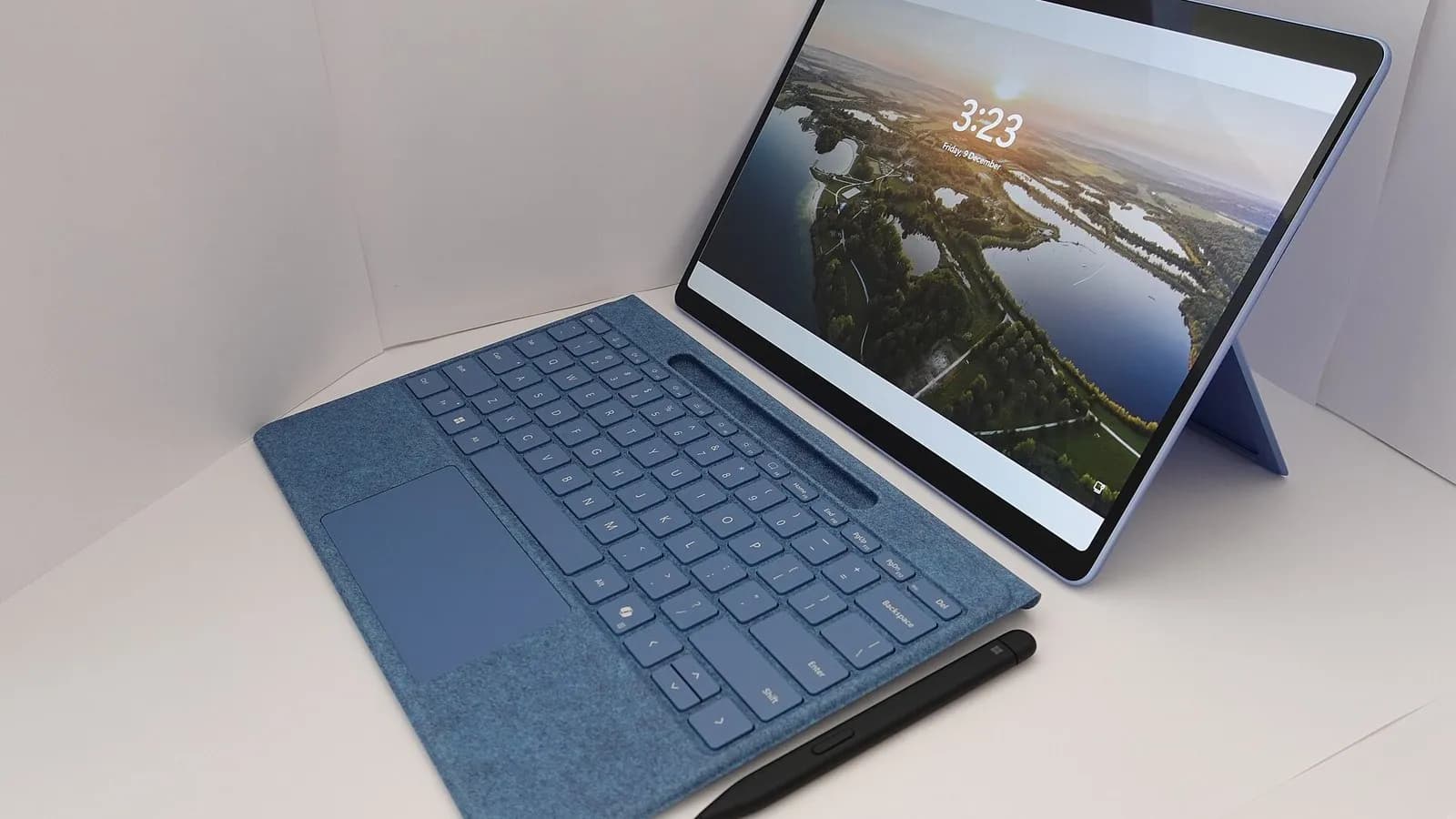 A blue tablet-style laptop with a detachable keyboard and a pen resting in front of it, its screen showing a landscape lock screen, photographed on 10 October 2024, a file photograph illustrative of a laptop and not of Flint or any Recursive product
