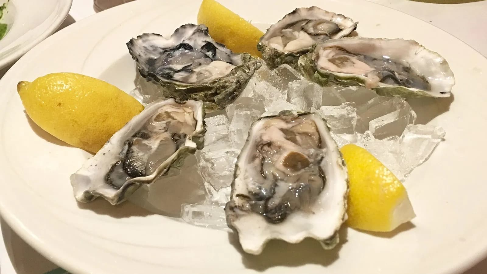 Five oysters in their shells on crushed ice with lemon wedges on a white plate, photographed on 16 December 2017, a file photograph illustrative of raw oysters and not of the recalled Little Wicomico River product