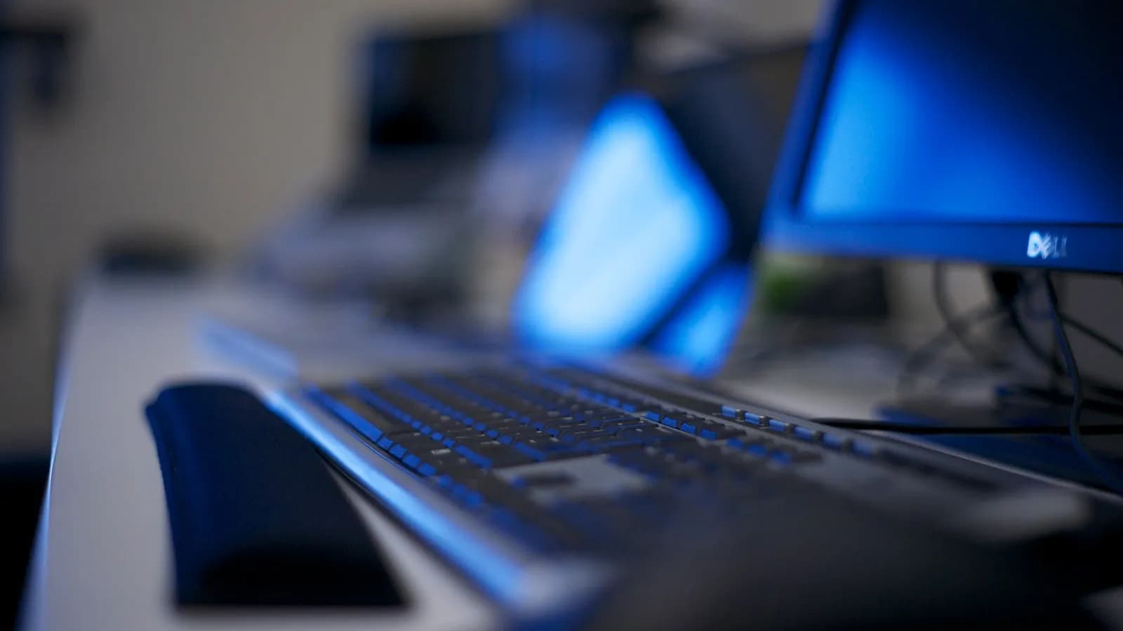 Computers on a long office desk, photographed out of focus. The keys used in the exploit were traced to a developer machine holding backups for seven of them