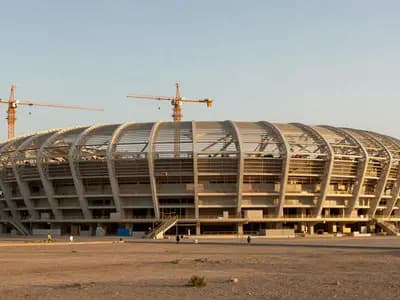 A large stadium under construction in a desert at golden hour