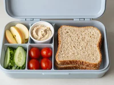 An open school lunchbox packed with fruit, sandwiches and snacks