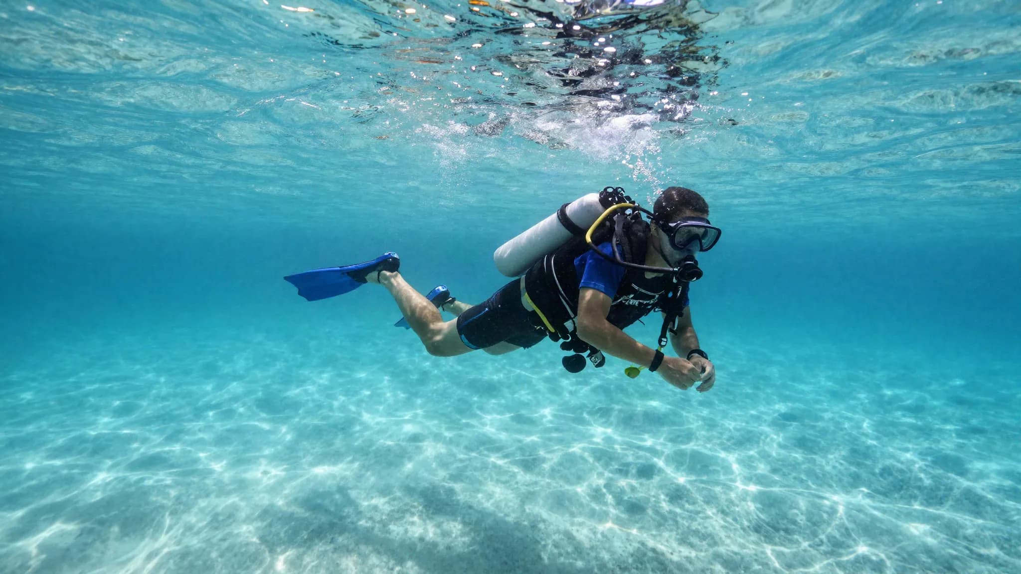 A scuba diver holding a safety stop in shallow turquoise water