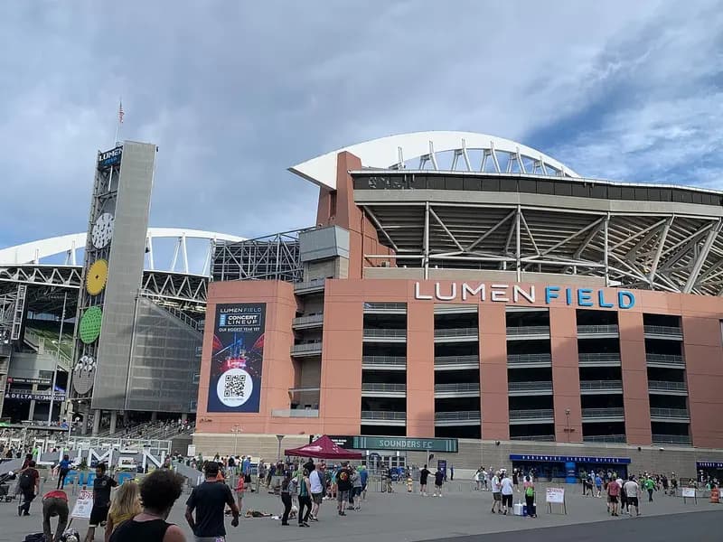 The exterior of Lumen Field in Seattle with its name above the entrance, its clock tower and curved roof, and fans gathered outside, photographed on 15 July 2023, a file photograph of the stadium and not from Sunday night's game