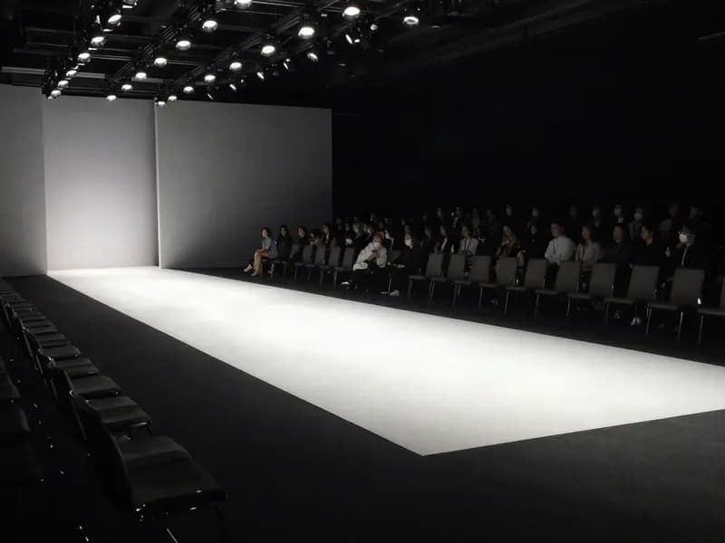 A lit empty runway with the audience seated on either side before a show