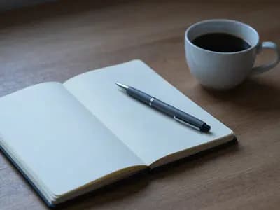 An open notebook and pen on a desk in morning light