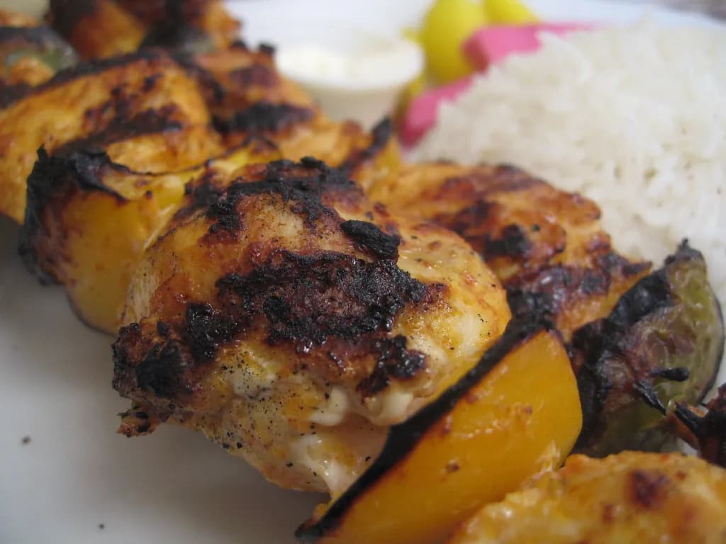 Golden-brown grilled shish tawook skewers with charred chicken and warm spices