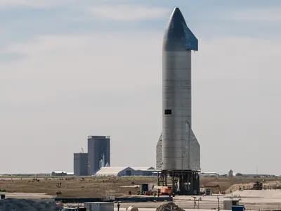 A stainless-steel Starship prototype standing on its launch mount at SpaceX's Starbase site in Texas with the build site behind it, photographed on 16 January 2021, a file photograph of SpaceX hardware and not from this week's earnings call