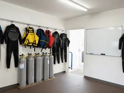 A dive centre briefing area with rental equipment racked behind a group of students
