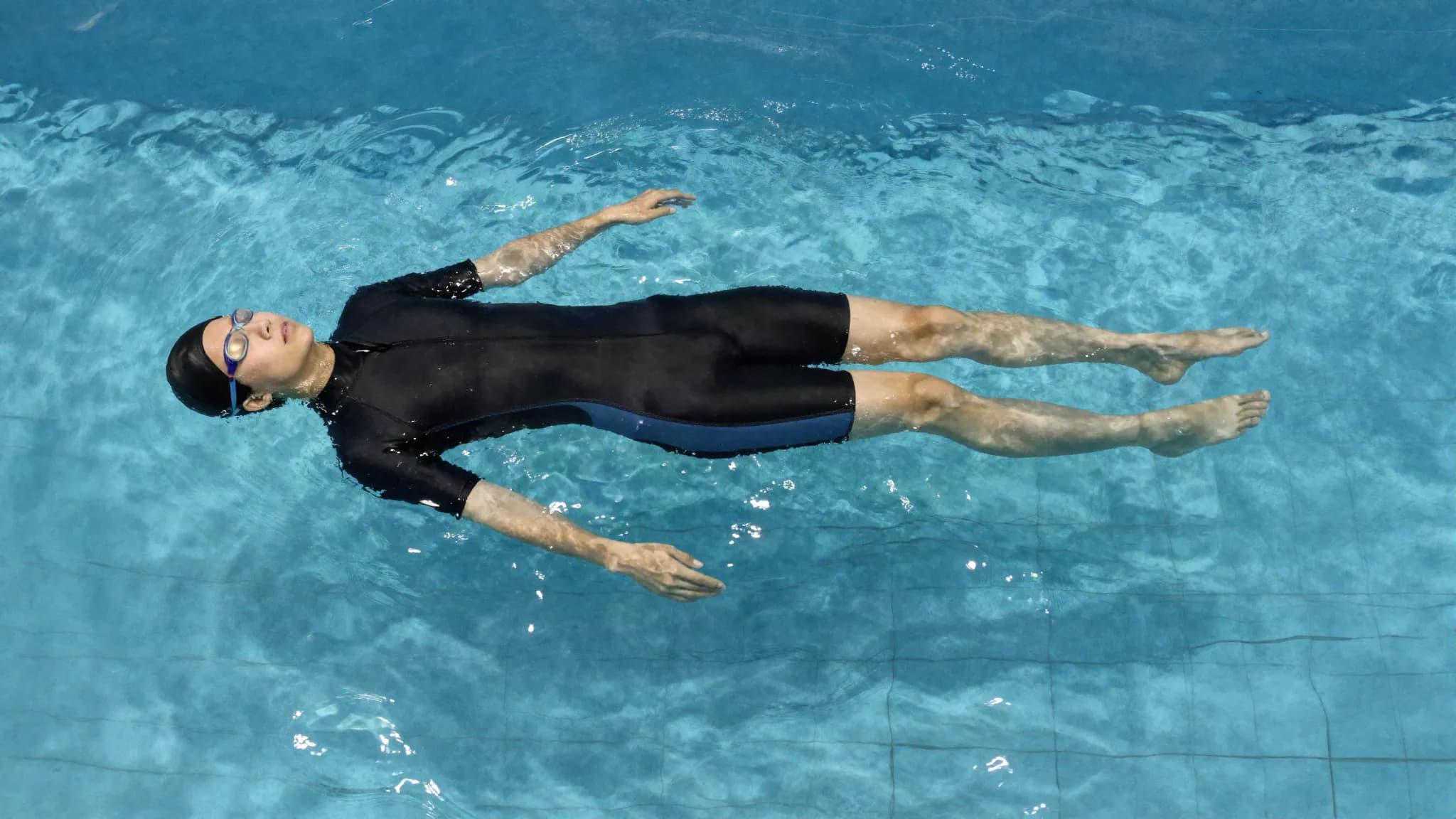 A swimmer floating face down and motionless in a still pool