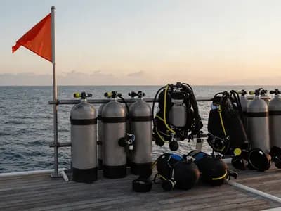 Scuba cylinders and kit lined up on a dive boat deck at sunrise