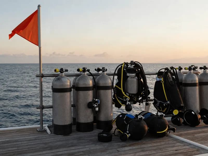 Scuba cylinders and kit lined up on a dive boat deck at sunrise