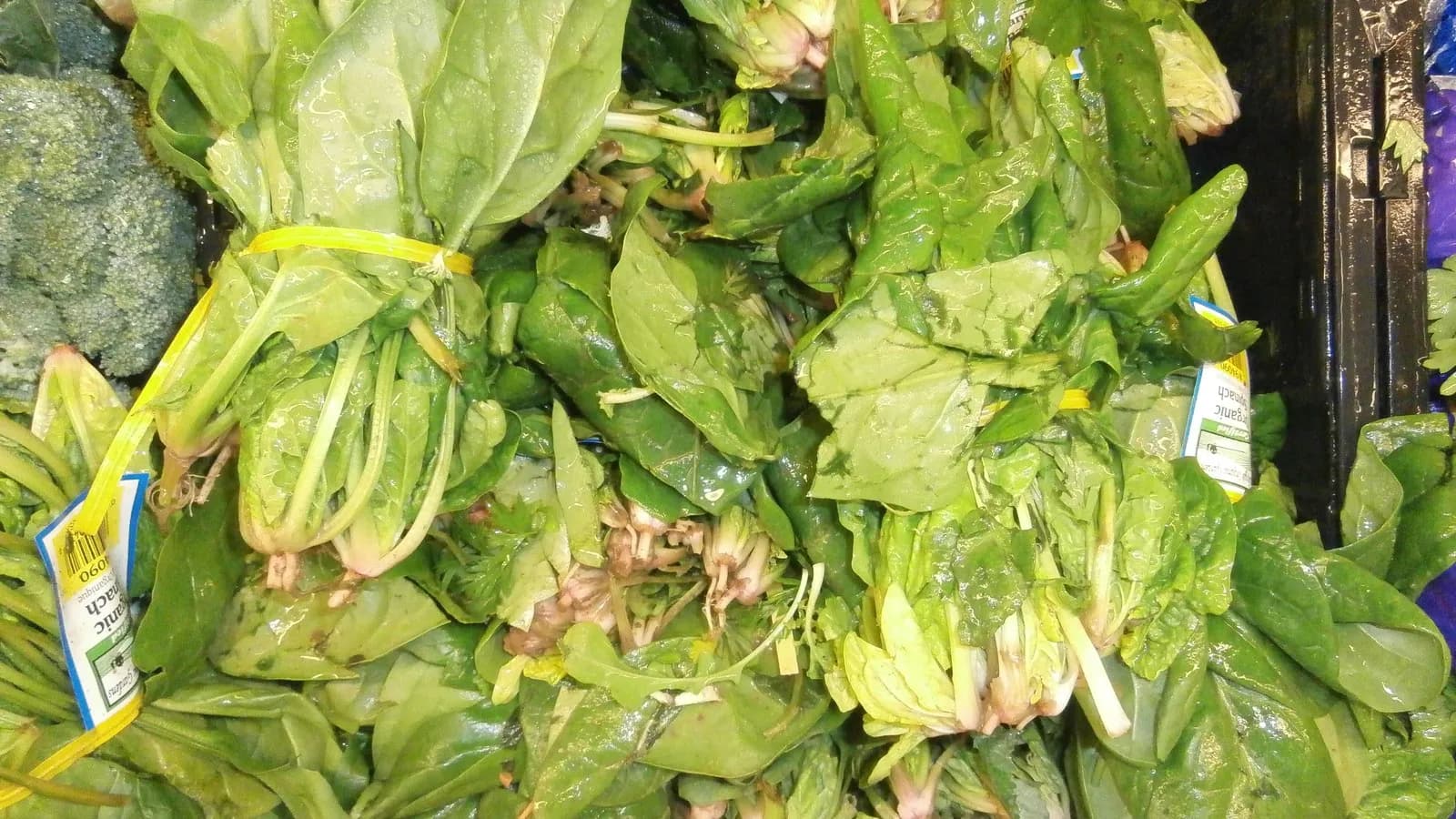Bunches of fresh spinach stacked in a market crate