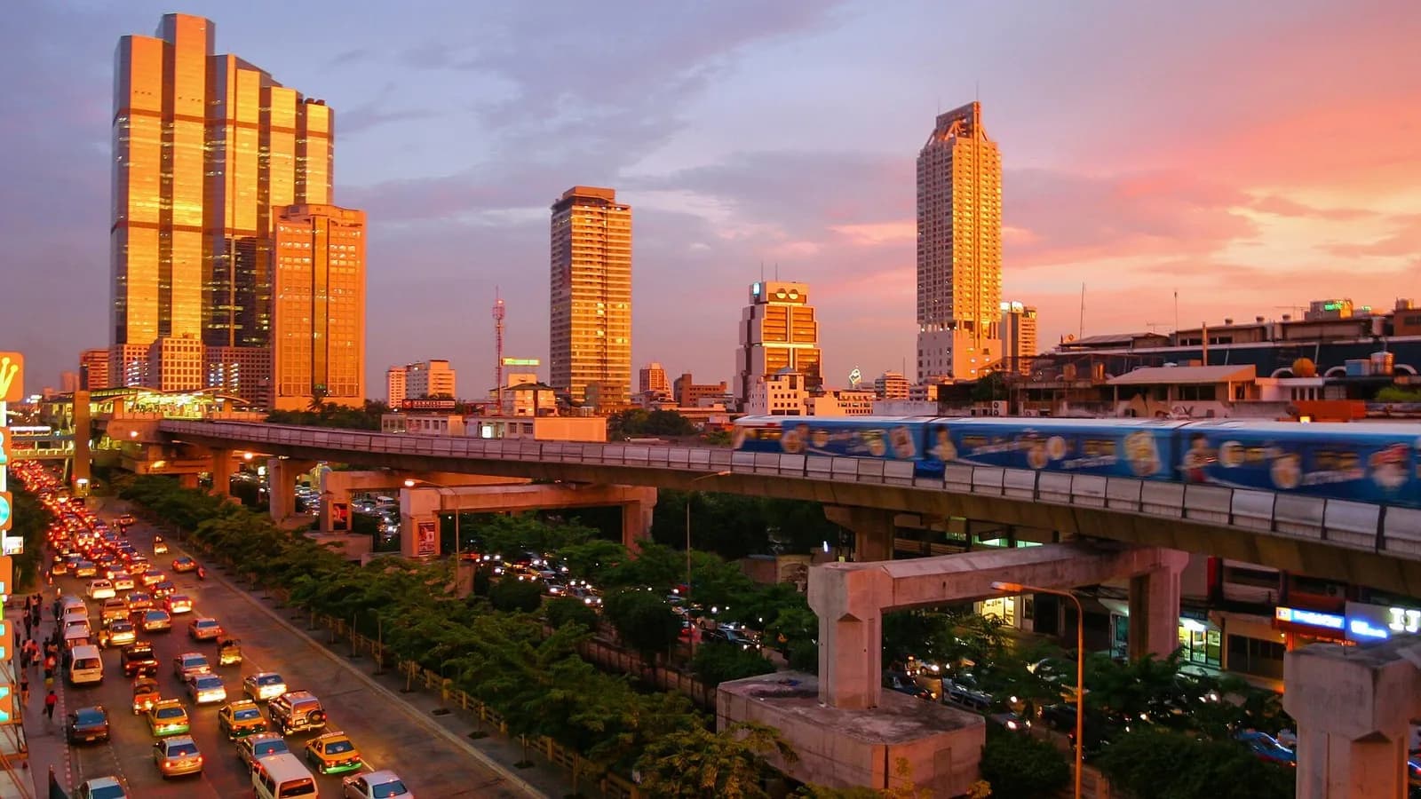 The Bangkok skytrain and glass towers glowing at sunset above a busy road near Silom, photographed on 4 June 2004, a file photograph of the city and not of this year's visitor numbers