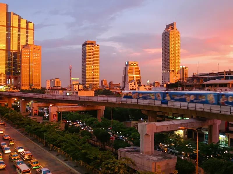 The Bangkok skytrain and glass towers glowing at sunset above a busy road near Silom, photographed on 4 June 2004, a file photograph of the city and not of this year's visitor numbers