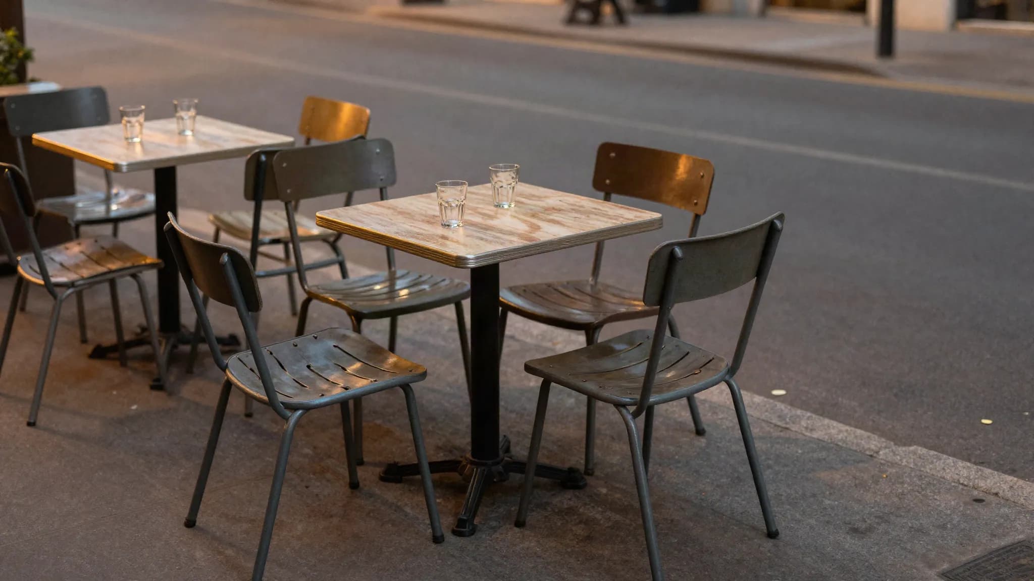 Outdoor cafe tables on a quiet pavement in the evening