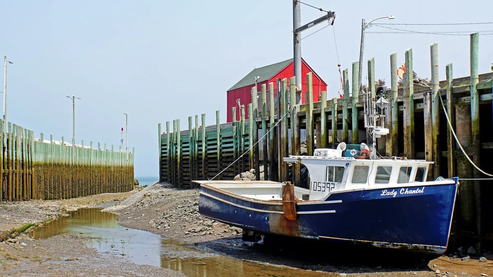 A fishing boat resting on the mud at low tide in Halls Harbour, Nova Scotia, on the Bay of Fundy where the tidal range is among the largest in the world, photographed in July 2017