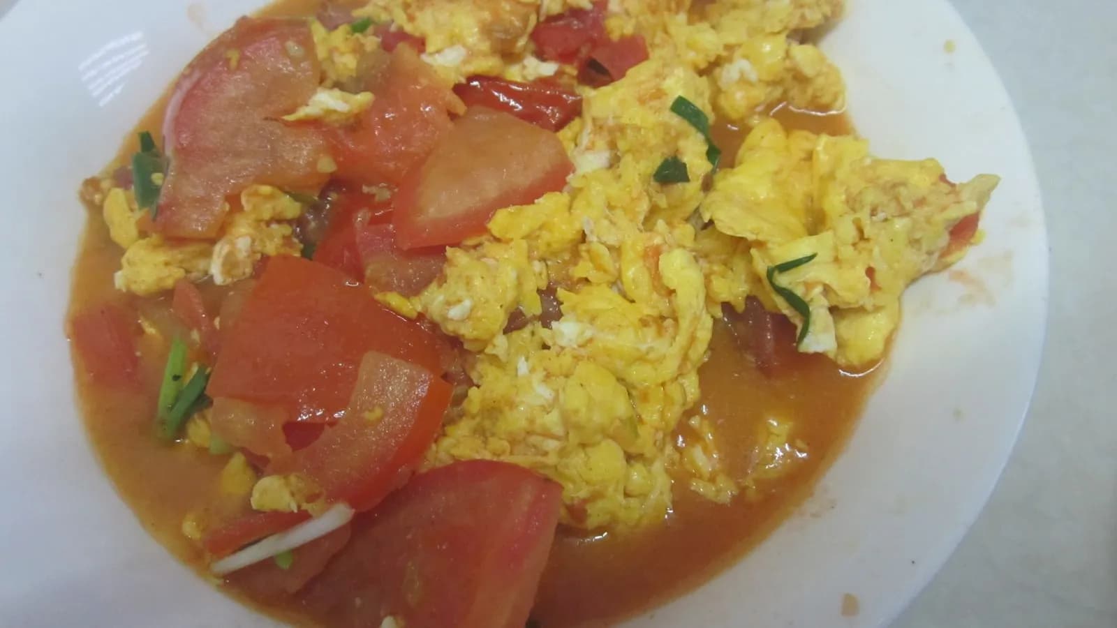 A plate of Chinese stir-fried tomato with scrambled eggs and spring onion, in a Hunan-style home dish, photographed in July 2019