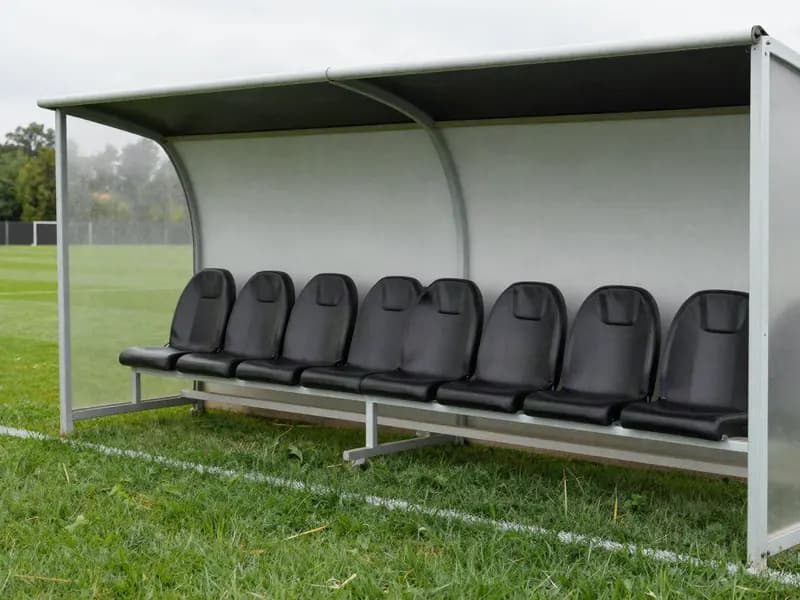 An empty dugout beside a football pitch