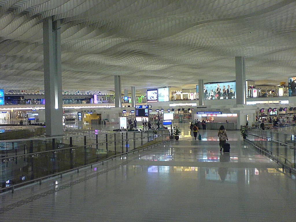 A traveler at a European airport biometric border control kiosk with a departure board in the background