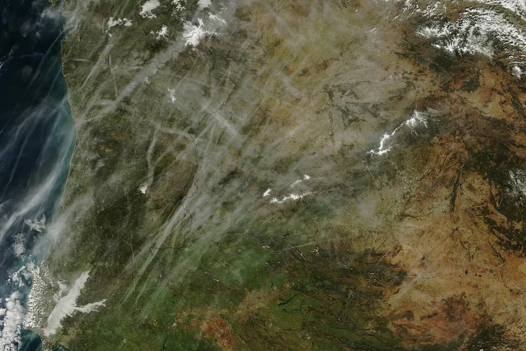 A weather research aircraft flying beneath rain clouds over an arid landscape