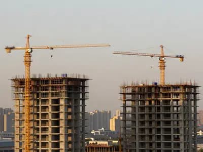 Cranes above a construction site against a city skyline