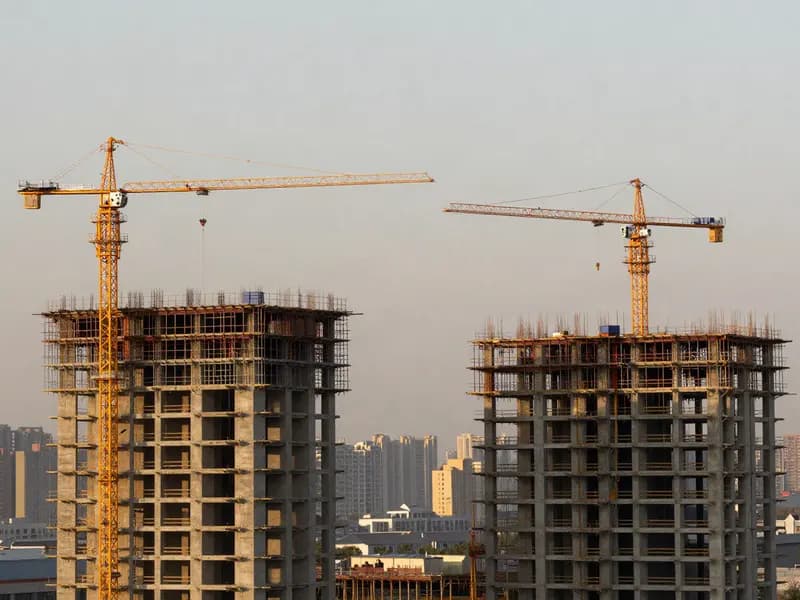 Cranes above a construction site against a city skyline
