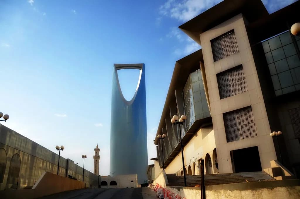 The modern skyline of Abu Dhabi with glass towers along the waterfront under a bright midday sky.