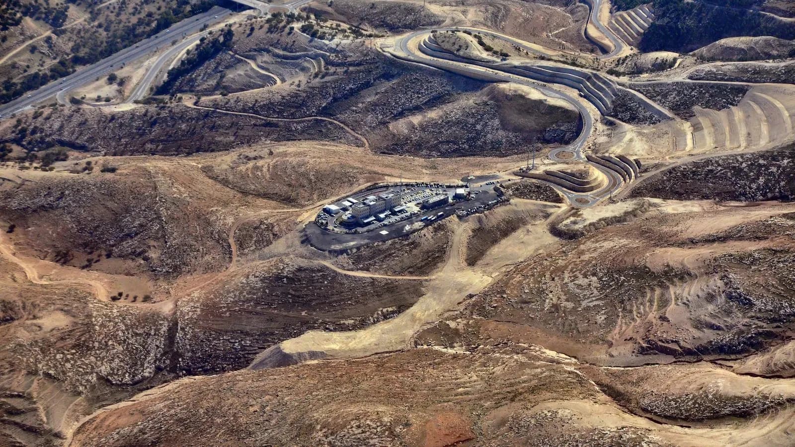 The E1 area east of Jerusalem seen from the air, with the Ma'ale Adumim interchange and the police headquarters built on the site, and bare hills around them