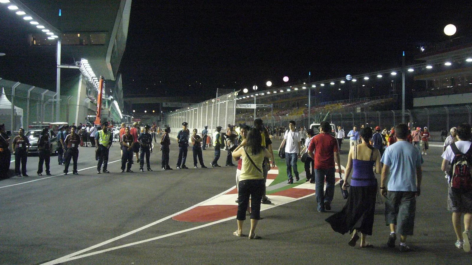Staff and visitors walking along the pit entrance of the Marina Bay Street Circuit in Singapore at night under floodlights, photographed in September 2008, a file photograph of the circuit and not of Sunday's race