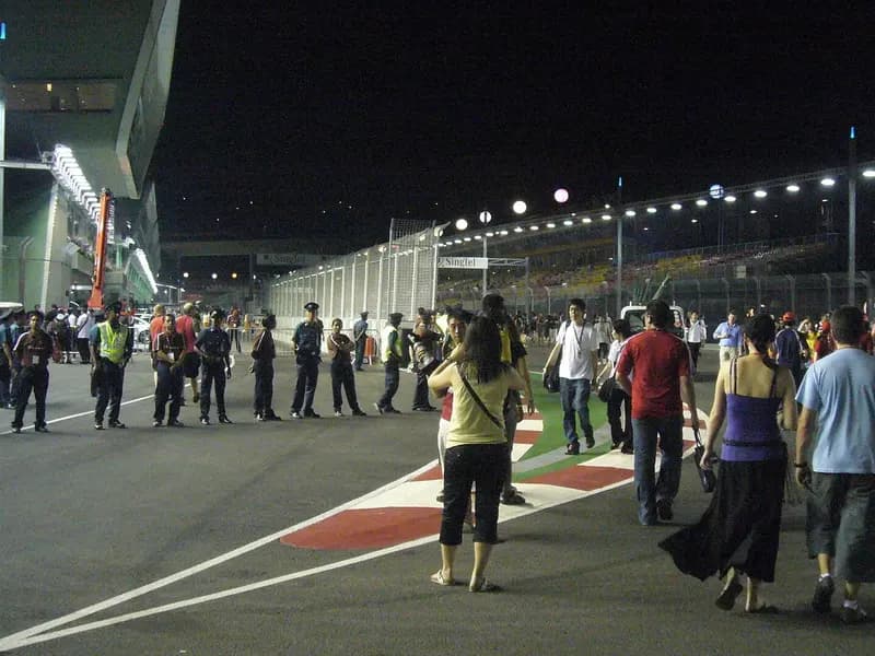 Staff and visitors walking along the pit entrance of the Marina Bay Street Circuit in Singapore at night under floodlights, photographed in September 2008, a file photograph of the circuit and not of Sunday's race