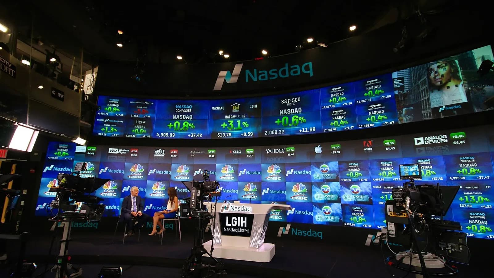 The curved wall of screens in the Nasdaq MarketSite broadcast studio in Times Square with presenters at a desk, photographed on 30 June 2015, a file photograph of the studio and not of Thursday's trading