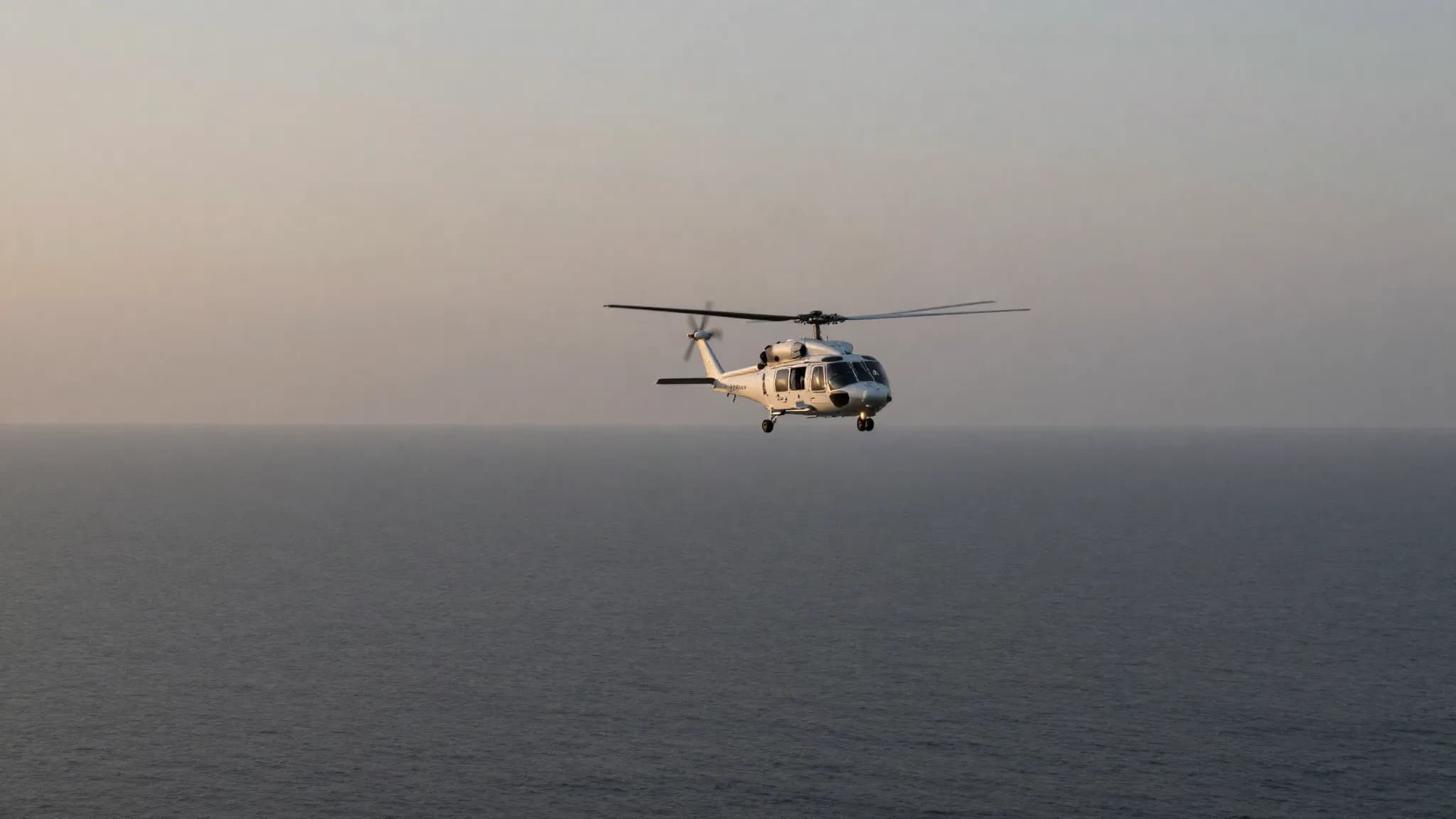 A rescue helicopter over open sea at dawn