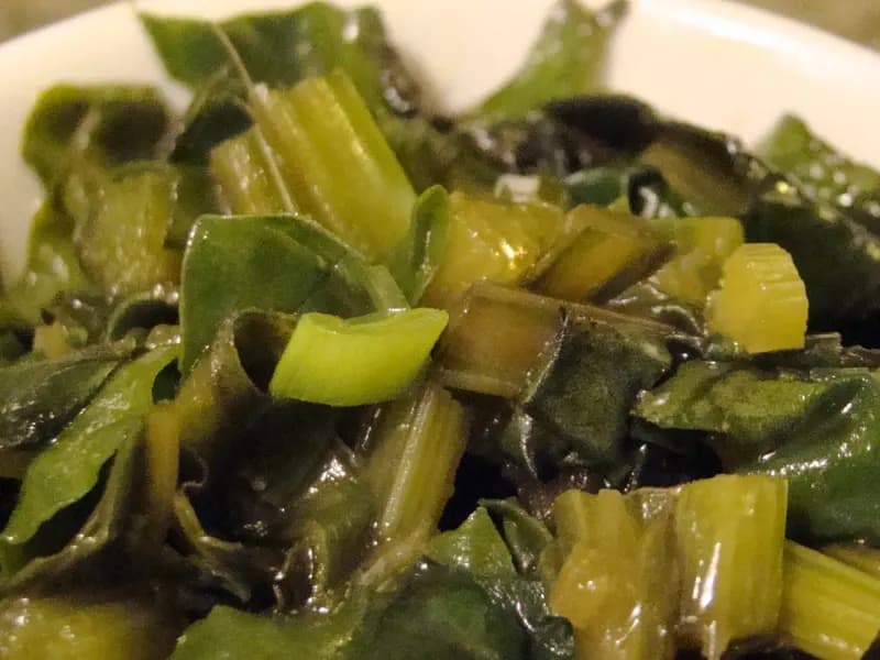 A bowl of cooked beetroot greens and their pale chopped stems, the two thirds of the bunch that most people throw away