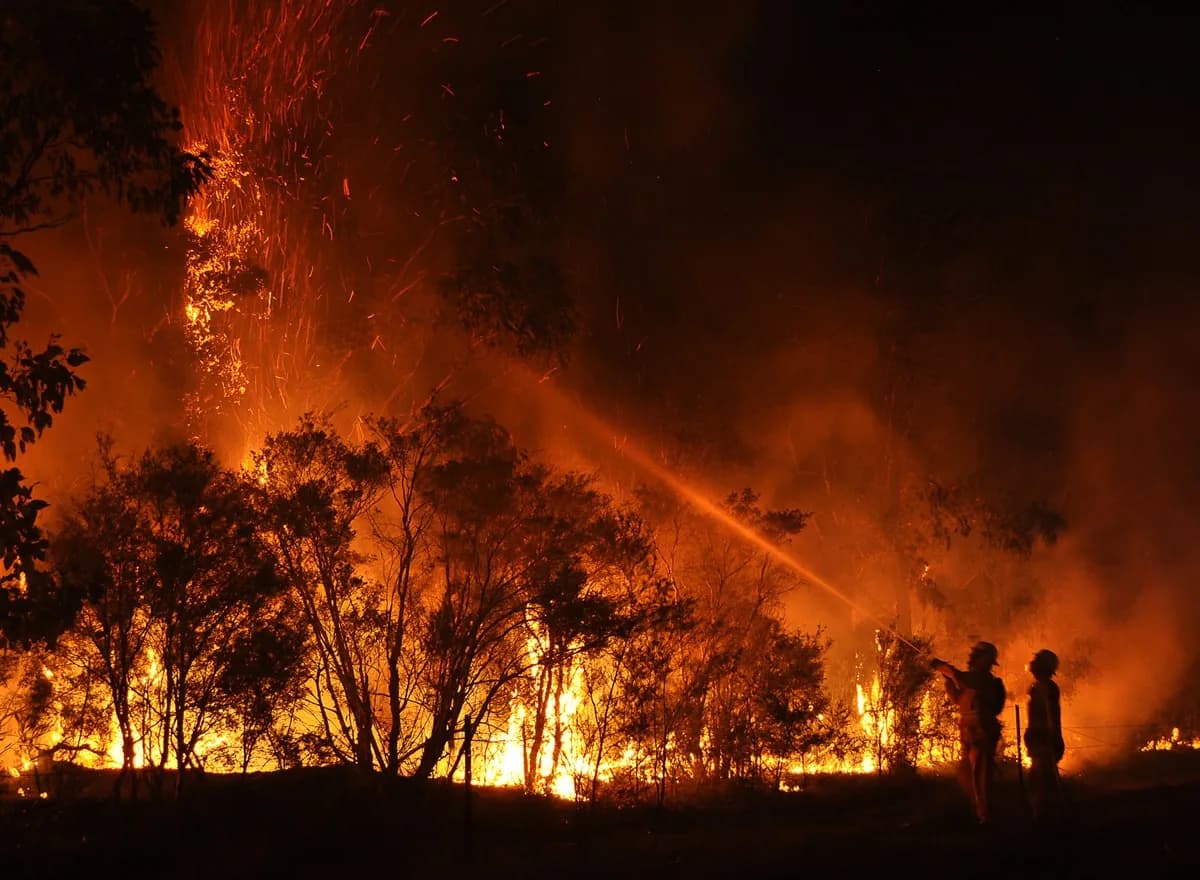 Dense wildfire smoke spreading across a European landscape beyond the visible fire line