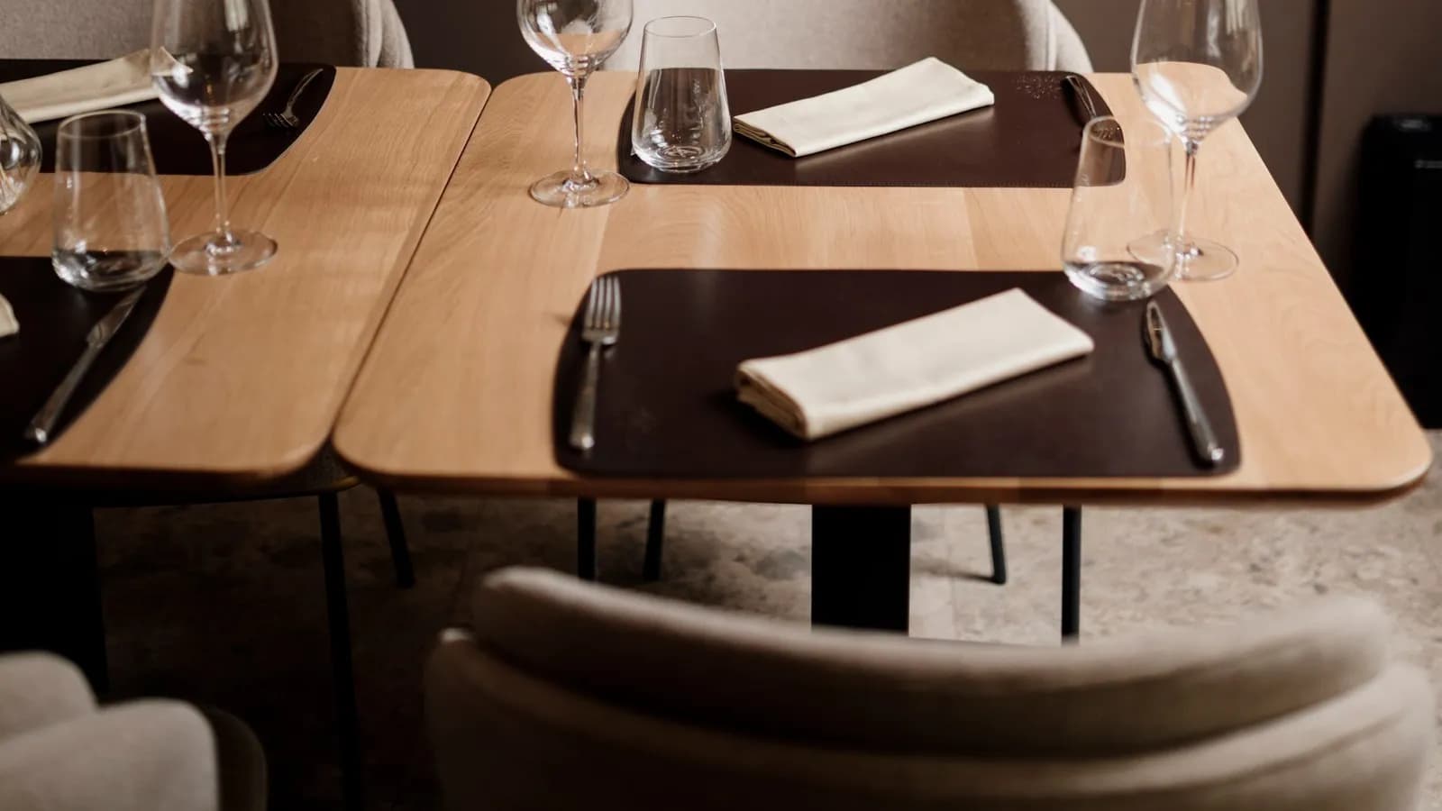 Tables laid with wine glasses, cutlery and folded napkins in a restaurant dining room