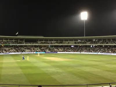 A floodlit cricket stadium during an evening match