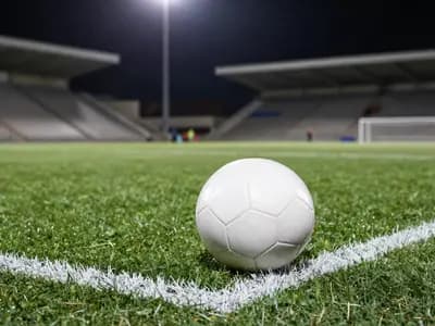 A football on floodlit turf inside the penalty area