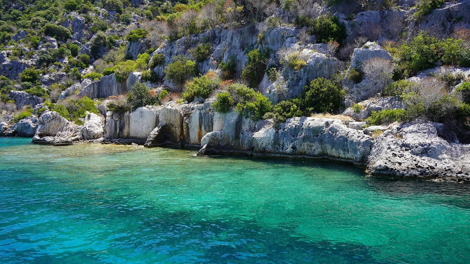 Turquoise water along the rocky shore of Kekova with the stone ruins of Simena above it, photographed on 24 June 2023, a file photograph of the coast near the site and not of the wreck or its excavation