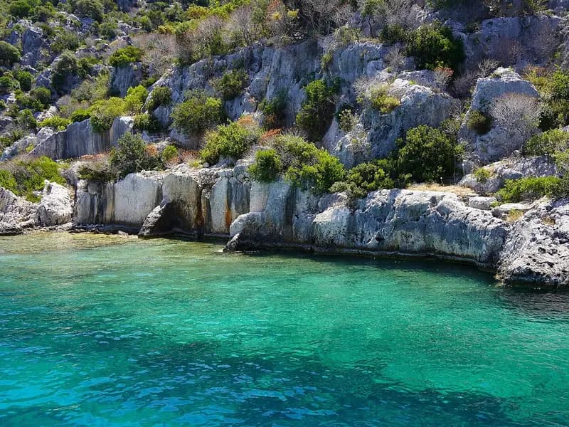 Turquoise water along the rocky shore of Kekova with the stone ruins of Simena above it, photographed on 24 June 2023, a file photograph of the coast near the site and not of the wreck or its excavation