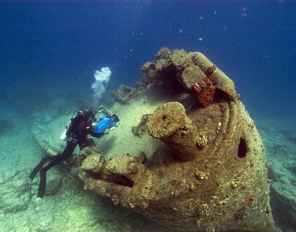 A scuba diver with a torch exploring the interior passage of a sunken shipwreck