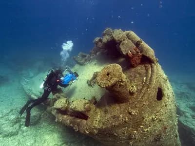 A scuba diver with a torch exploring the interior passage of a sunken shipwreck